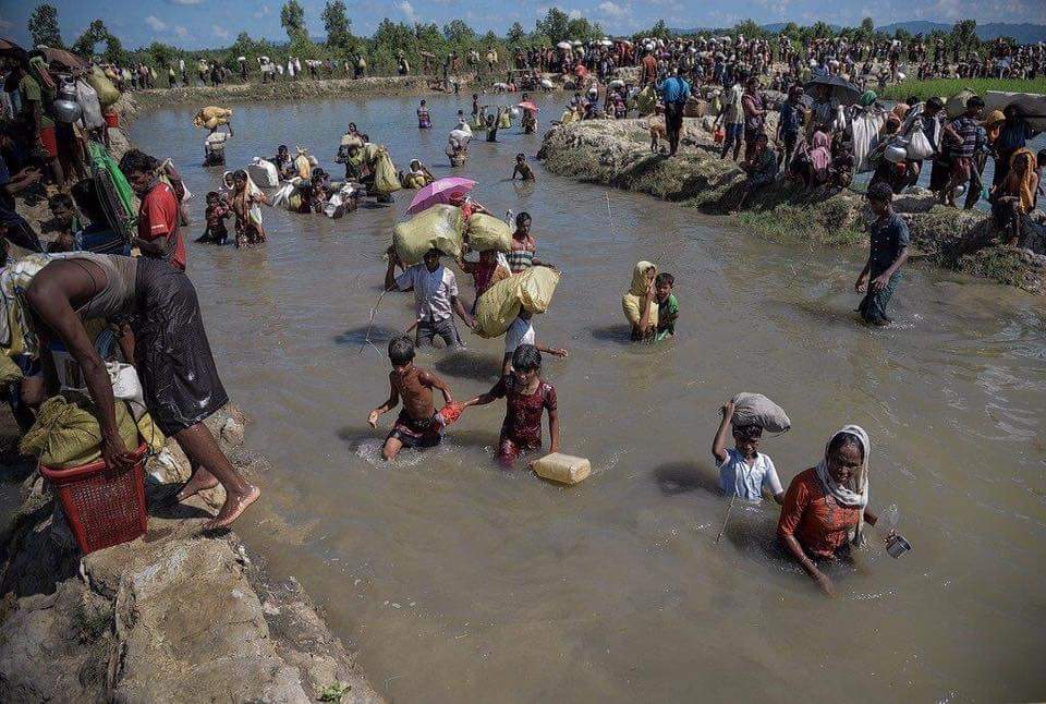Rohingya women and children fleeing persecution, crossing a river